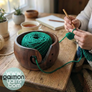 Cuenco para lana de madera de pino oscurecida - Garmon - Cuenco en primer plano con cake pequeño de lana verde sobre una mesa, con señora tejiendo una prenda a franjas de color