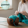 Cuenco para lana de madera de pino oscurecida - Garmon - Cuenco en primer plano con cake pequeño de lana color turquesa sobre una mesa, con señora tejiendo una prenda