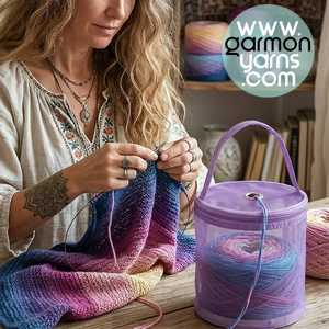 Bolsa dispensadora de lana - Garmon - mujer de estilo bohemio sentada junto a una mesa de madera, tejiendo con agujas circulares una prenda de colores degradados y, junto a ella, una bolsa de lana morada